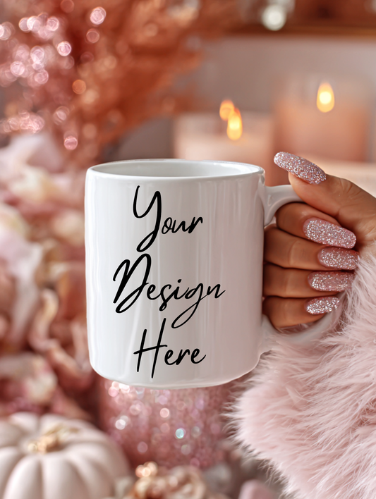 White mug with 'Your Design Here' text held by a hand with glittery nail polish against a festive background.